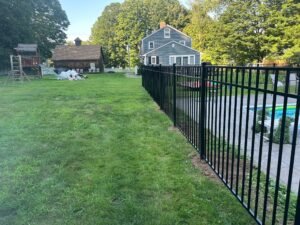 “Black aluminum grate fence surrounding backyard swimming pool”